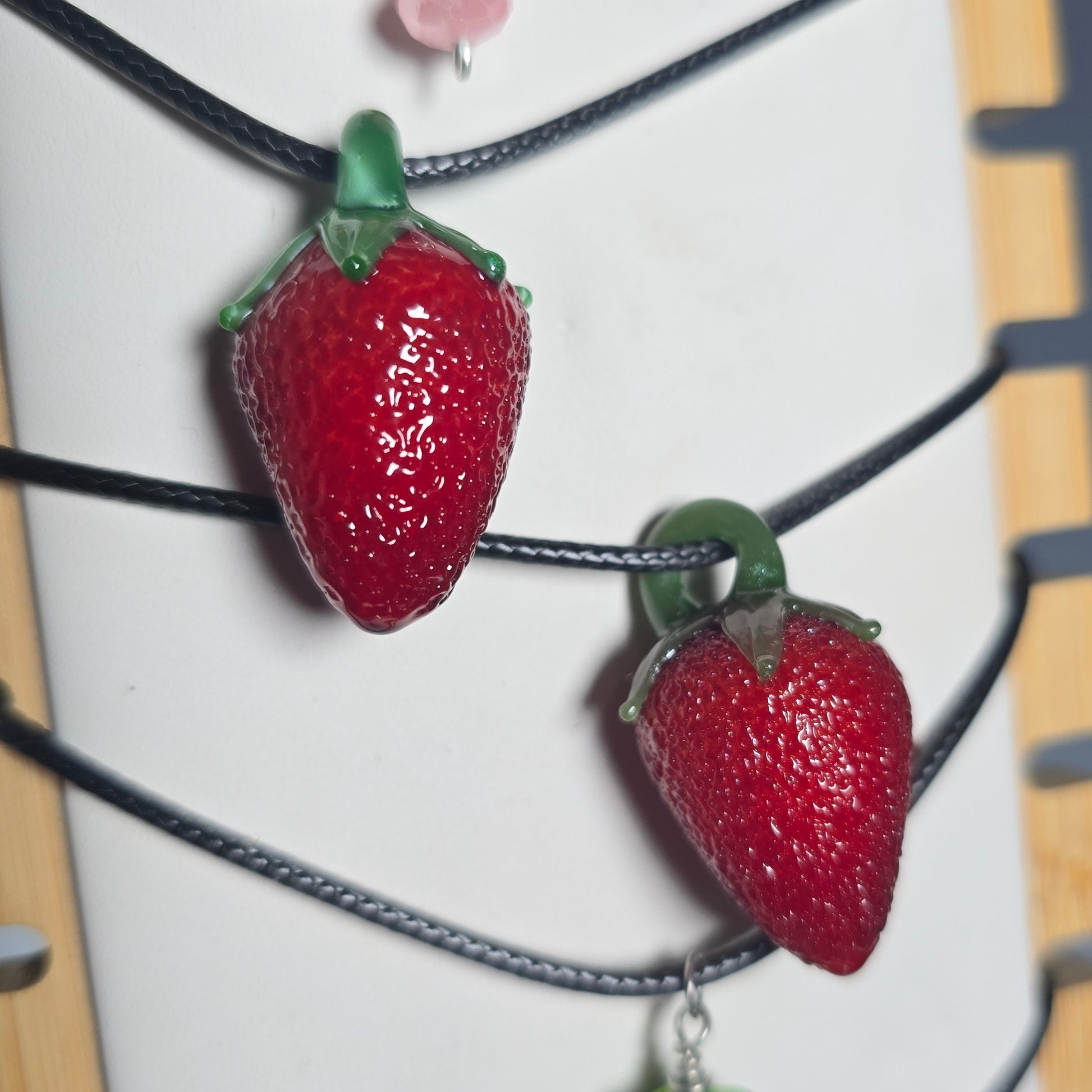 Strawberry and blackberry charms on a string with a white background
