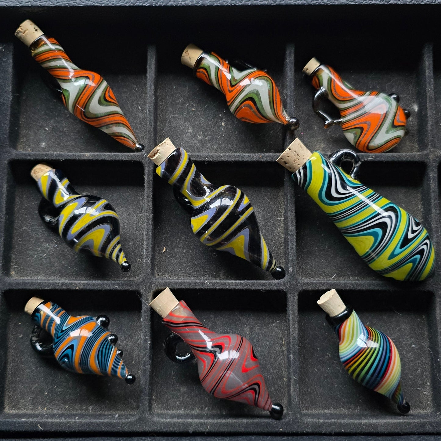 Colorful glass bottles arranged in a grid on a textured surface.