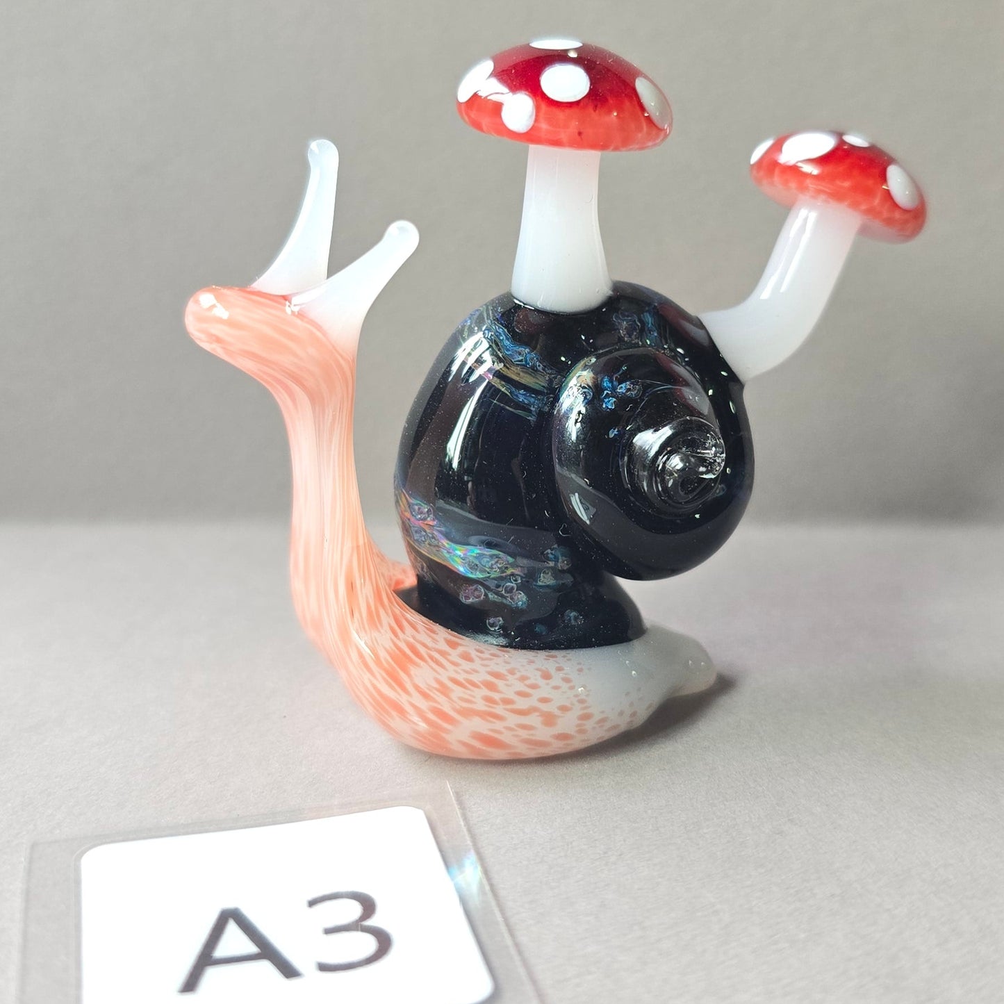 Glass snail with mushroom-shaped shells on a gray background