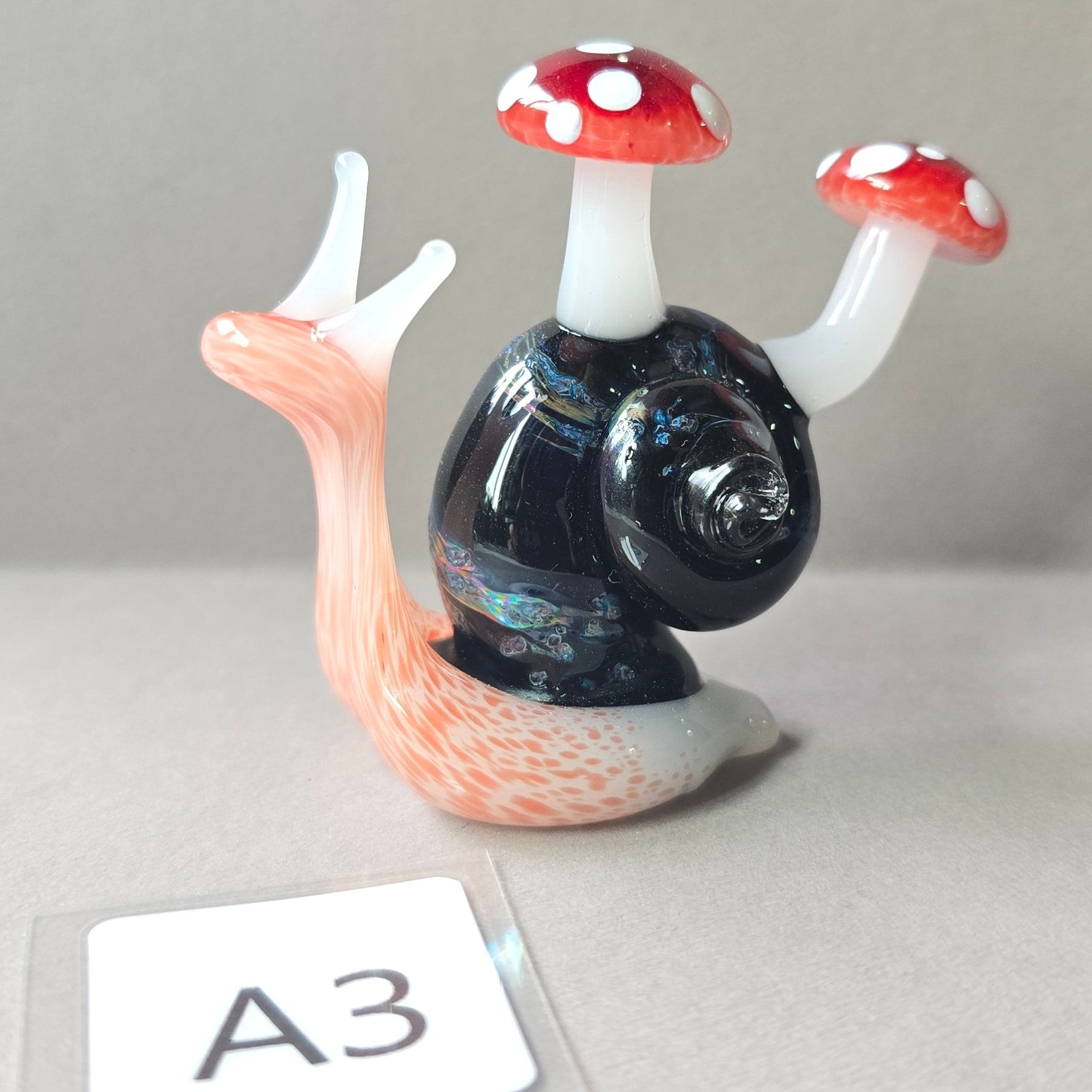 Glass snail with mushroom-shaped shells on a gray background