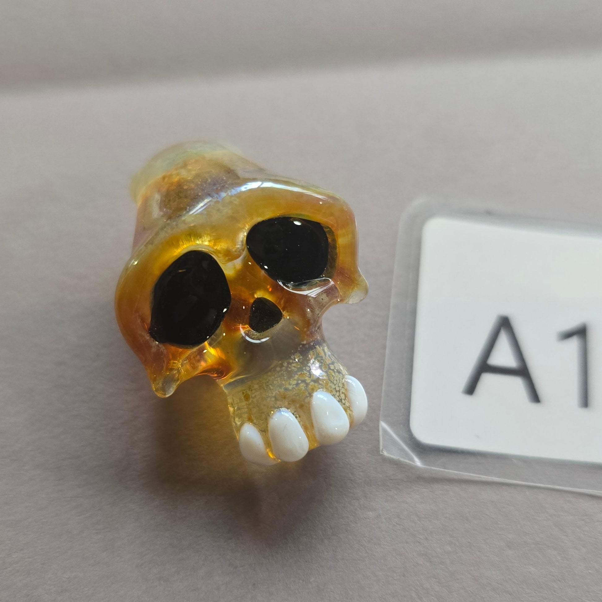 Skull-shaped object with yellow and black design on a gray background
